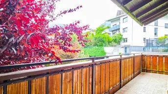 Balkon mit Holzgeländer und Blick auf die umliegende Bebauung und grüne Landschaft.