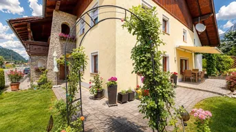 Charmantes Haus mit gepflegtem Garten, blühenden Pflanzen und einer gemütlichen Terrasse.