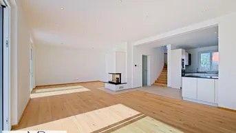 Helles, offenes Wohnzimmer mit Eichenparkett, modernem Kamin und Zugang zur Küche.
