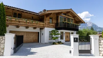 Luxuriöses Holzhaus im alpinen Stil mit Garage, Einfahrt und beeindruckendem Bergblick.