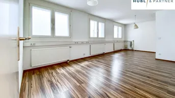 Geräumiger, heller Raum mit großen Fenstern, Holzfußboden und weißen Wänden, ideal für Wohn- oder Büronutzung.
