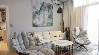 Modernes Wohnzimmer mit bequemen Sesseln, Sofa und einem runden Couchtisch auf hellem Teppich.