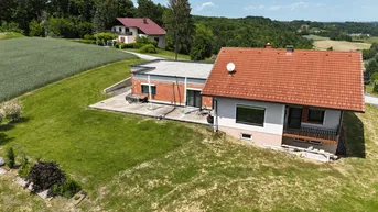 Luftaufnahme eines Hauses mit rotem Ziegeldach und einem Anbau in ländlicher Umgebung.