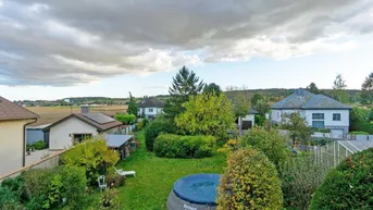 Weitläufiger Garten mit Pool und Blick auf die umliegende Landschaft unter bewölktem Himmel.