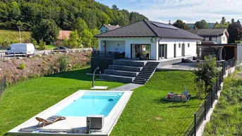 Modernes Einfamilienhaus mit Pool, großer Terrasse und weitläufigem Garten in Hanglage.