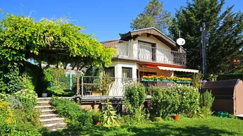 Charmantes Haus mit üppigem Garten, sonnigem Balkon und überdachter Terrasse unter einer Pergola.