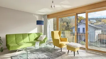 Helles Wohnzimmer mit großen Fenstern, Fliesenboden und Zugang zum Balkon.