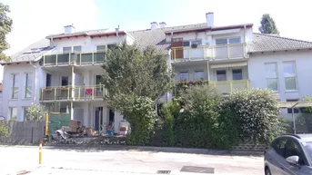 Mehrfamilienhaus mit mehreren Balkonen und einem gepflegten Gartenbereich im Vordergrund.