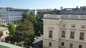 Blick von der Terrasse auf umliegende Gebäude, Bäume und einen Parkplatz in der Stadt.