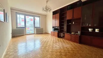 Geräumiges Wohnzimmer mit Parkettboden, großem Wandschrank und Zugang zu einem Balkon.