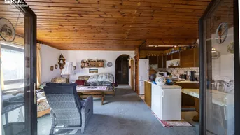 Gemütlicher Wohn- und Essbereich mit Holzbalkendecke und Zugang zur Terrasse.