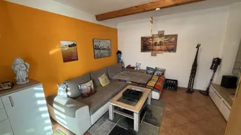 Gemütliches Wohnzimmer mit großer Eckcouch, Holzbalken und farbiger Akzentwand.