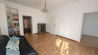 Wohnzimmer mit Fischgrätparkett, Ledersofa und traditionellem Kachelofen.