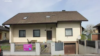 Vorderansicht eines Einfamilienhauses mit Satteldach und integrierter Garage im Untergeschoss.