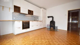 Helle Küche mit weißen Schränken, Holztheke, gemustertem Fliesenspiegel und gemütlichem Holzofen.
