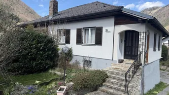 Einfamilienhaus mit Steintreppe, Vorgarten und Blick auf die umliegenden Berge.