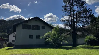 Rückansicht des Hauses mit großem Garten und weitem Blick auf die umliegenden Berge.