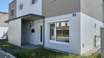 Moderne Doppelhaushälfte mit weißer und grauer Fassade und kleinem Vorgartenbereich.