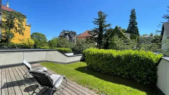 Sonnige Terrasse mit Holzdeck, Rasenfläche und bequemen Liegestühlen, umgeben von grünen Hecken.