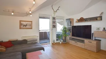 Helles Wohnzimmer mit Holzboden, gemütlichem Sofa und Zugang zum Balkon.