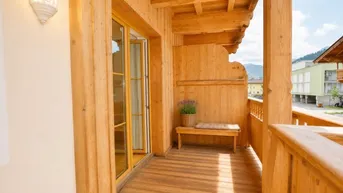 Holzbalkon mit Sitzgelegenheit und Blick auf die umliegende Berglandschaft.