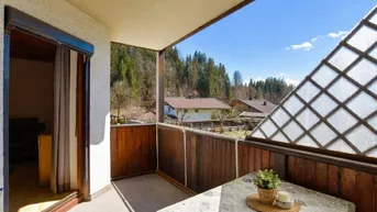 Balkon mit Holzelementen, Tisch und Stühlen, bietet einen weiten Blick auf die bewaldete Landschaft.