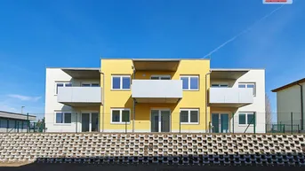 Modernes Mehrfamilienhaus mit gelber Fassade und Balkonen unter blauem Himmel.