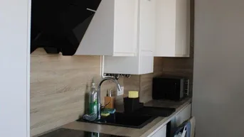 Moderne Küche mit weißen Schränken, Holz-Arbeitsplatte und integrierten Geräten.