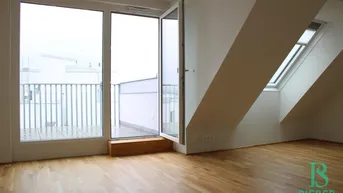 Heller Wohnraum mit Parkettboden, Zugang zum Balkon und Dachschrägenfenstern.