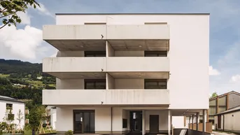 Modernes Wohngebäude mit mehreren Balkonen und einem überdachten Eingangsbereich.