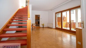 Helles Wohnzimmer mit Parkettboden, Holztreppe und Zugang zu einer Terrasse.