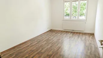 Helles, leeres Zimmer mit Laminatboden und Fensterblick ins Grüne, ideal als Wohn- oder Schlafzimmer.