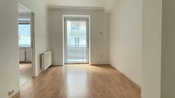 Geräumiges Zimmer mit Parkettboden und Zugang zu einem kleinen Balkon, ideal für ein Wohnzimmer.