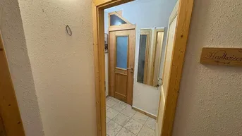 Flur mit Holztüren und Fliesenboden, der zu weiteren Räumen führt.