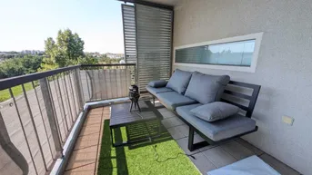 Gemütlicher Balkon mit Kunstrasen, Sitzgelegenheiten und Blick ins Grüne, perfekt zum Entspannen.