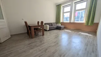 Helles Wohn- und Esszimmer mit Laminatboden, großzügigen Fenstern und einem Esstisch.
