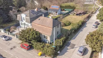 Luftaufnahme eines Wohnhauses mit Satteldach und umliegender Nachbarschaftsstraße in sonniger Lage.