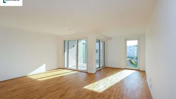 Helles Wohnzimmer mit Parkettboden und Zugang zu einem Außenbereich, durchflutet von natürlichem Licht.