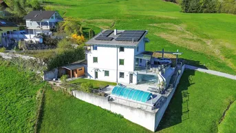 Luftaufnahme des Hauses mit Solaranlage auf dem Dach, Poolbereich und weitläufiger grüner Umgebung.