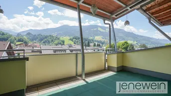 Große überdachte Terrasse mit Bergblick und grüner Bodenfläche.