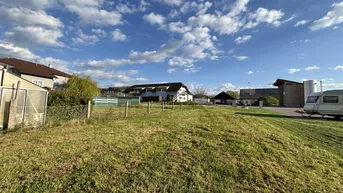 Weitläufiges Grundstück mit grüner Wiese und Blick auf umliegende Häuser unter blauem Himmel.