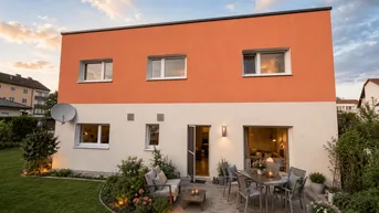 Moderne Hausfassade mit großer möblierter Terrasse und gepflegtem Garten bei Sonnenuntergang.