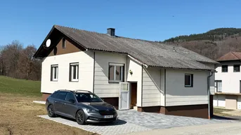 Einfamilienhaus mit Satteldach und gepflasterter Auffahrt in ländlicher Umgebung.