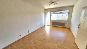Helles Wohnzimmer mit Laminatboden und Zugang zu einem Balkon, ideal für entspannte Stunden.