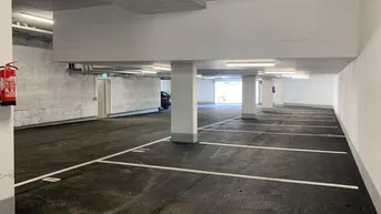 Geräumige Tiefgarage mit markierten Stellplätzen, guter Beleuchtung und Brandschutzvorrichtungen.