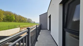 Geräumiger Balkon mit Fliesenboden und weitem Blick ins Grüne.
