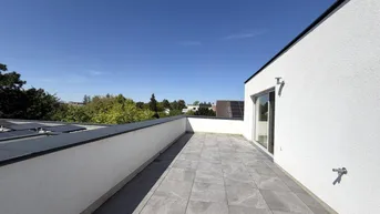 Geräumige Dachterrasse mit Fliesenboden und weitem Blick unter blauem Himmel.