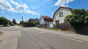 Blick auf eine ruhige Wohnstraße mit Einfamilienhäusern unter blauem Himmel an einem sonnigen Tag.