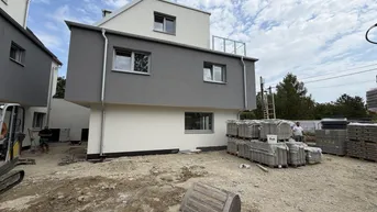Neubau-Doppelhaushälfte im Rohbauzustand mit Baumaterialien auf dem Grundstück.