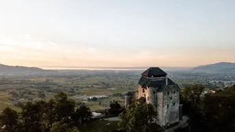 Historisches Gebäude auf einem Hügel mit weitem Blick über die Landschaft bei Sonnenuntergang.